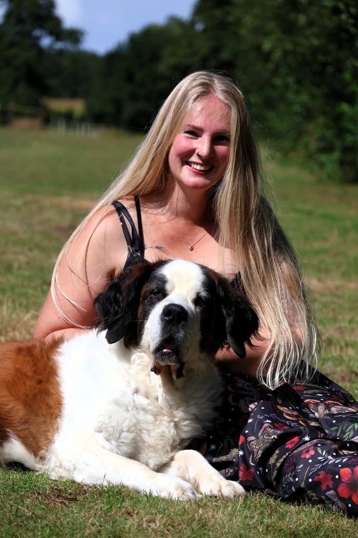 Anouk in het gras met een liggende Sint-Bernard