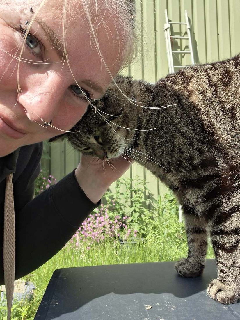 Anouk met een cyperse kat die zijn kop tegen haar aan drukt